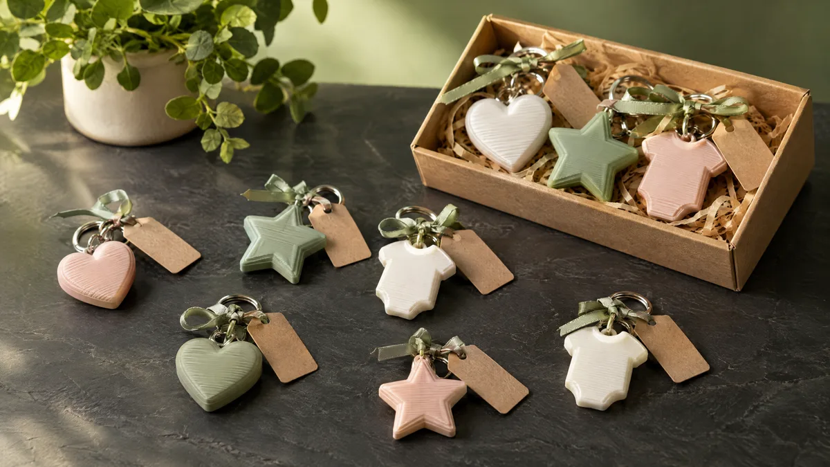 Chaveiros lembrancinha impressos em 3D em forma de coração, estrela e bodinho, em tons pastel, com fita verde e etiquetas de papel